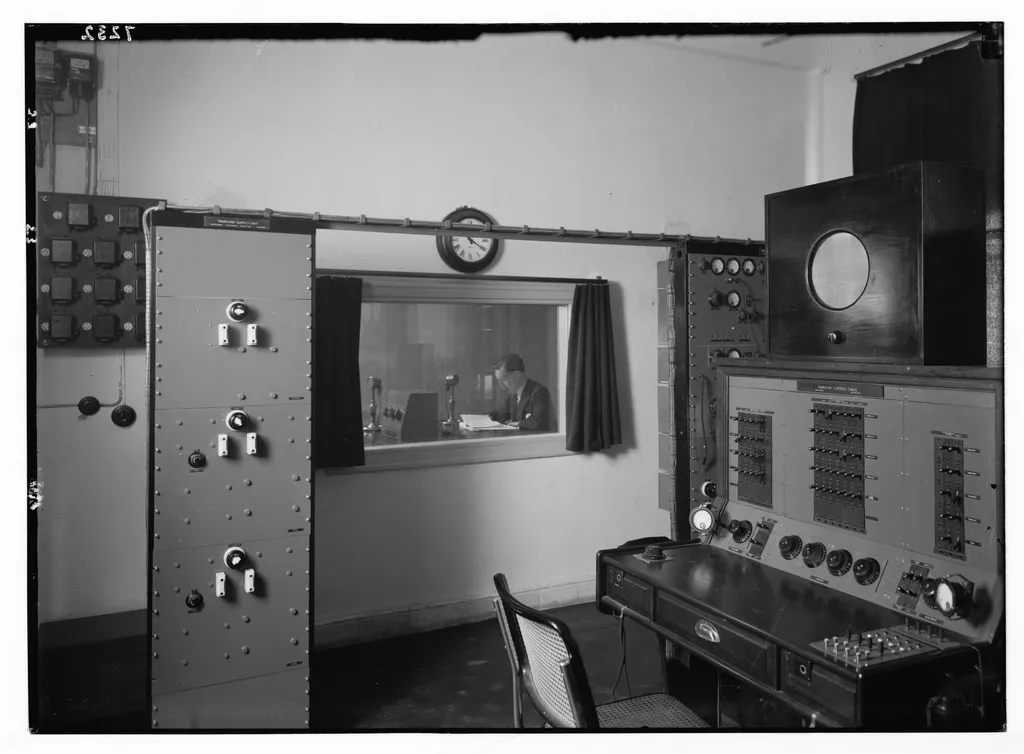 A 1930s radio station control room, with the announcer behind glass
