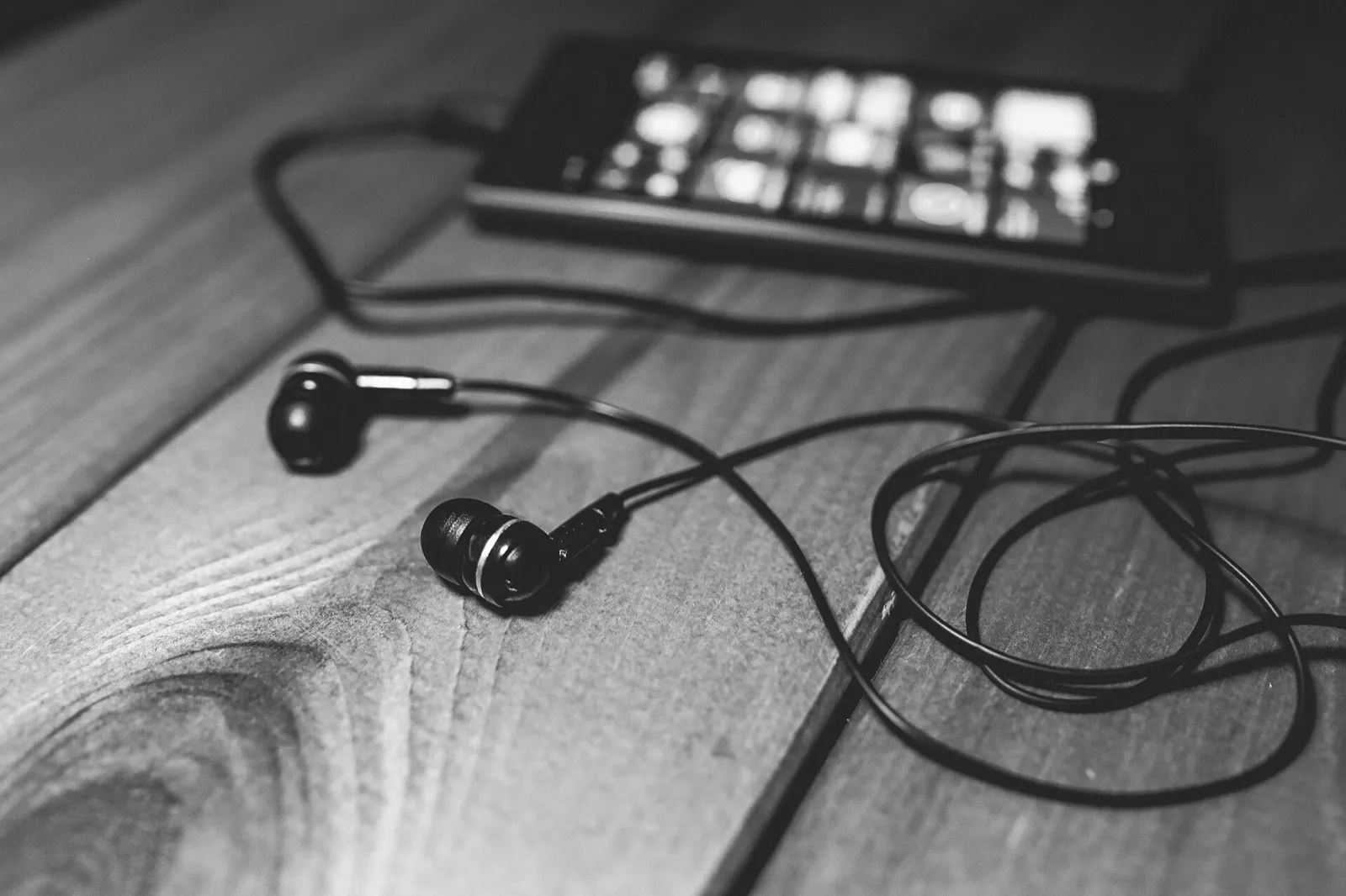 Earbuds and a phone on a wooden table