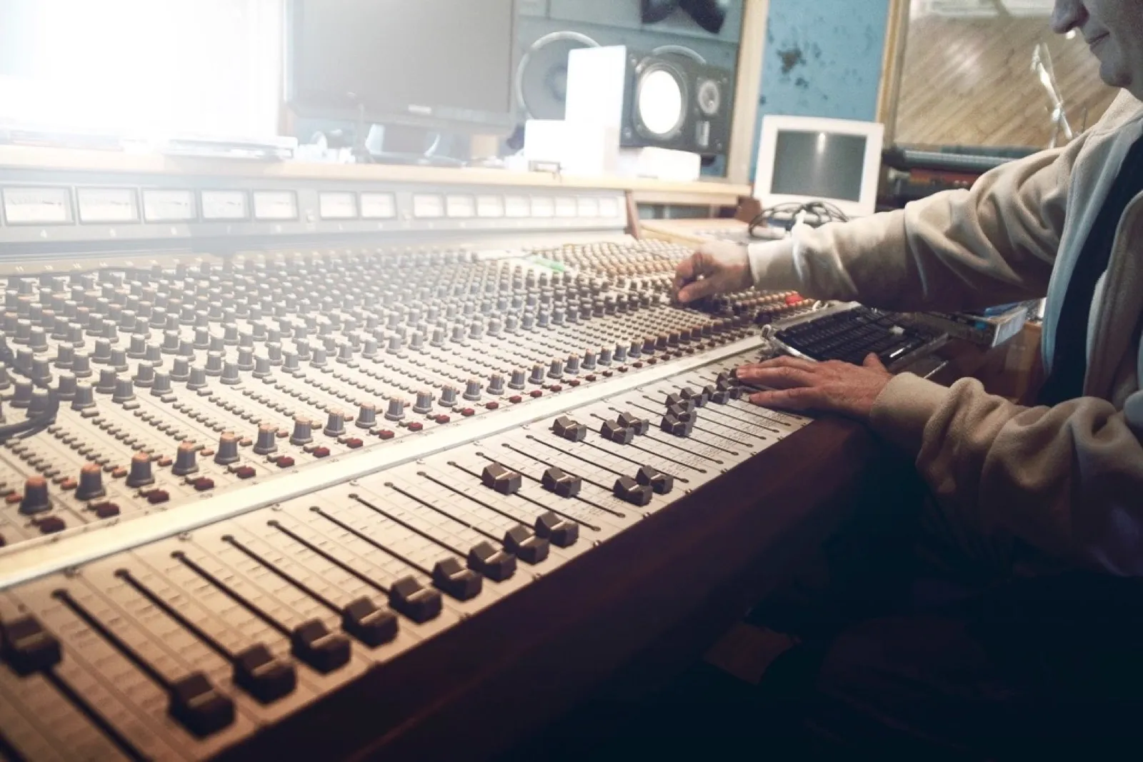 Hands working a mixing console in a studio