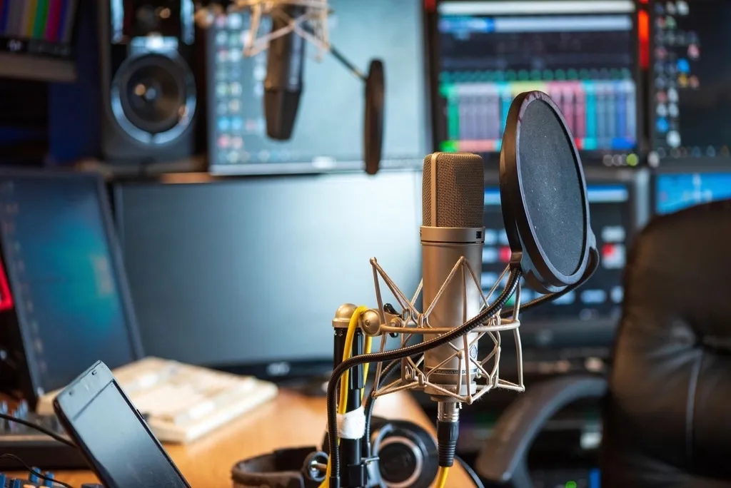 A studio desk with a microphone and audio software open on the monitors