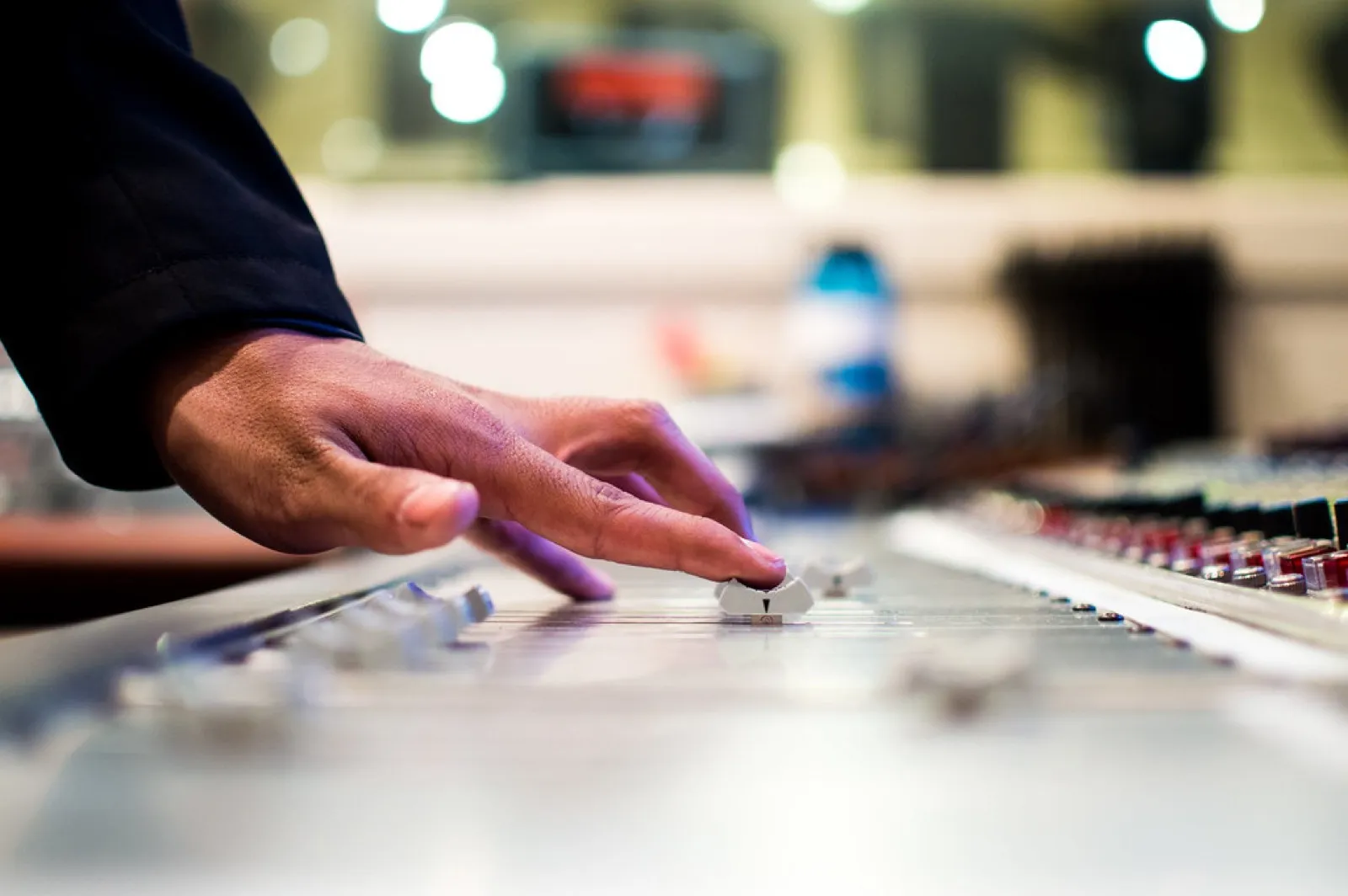 Finger nudging a fader on a mixing console