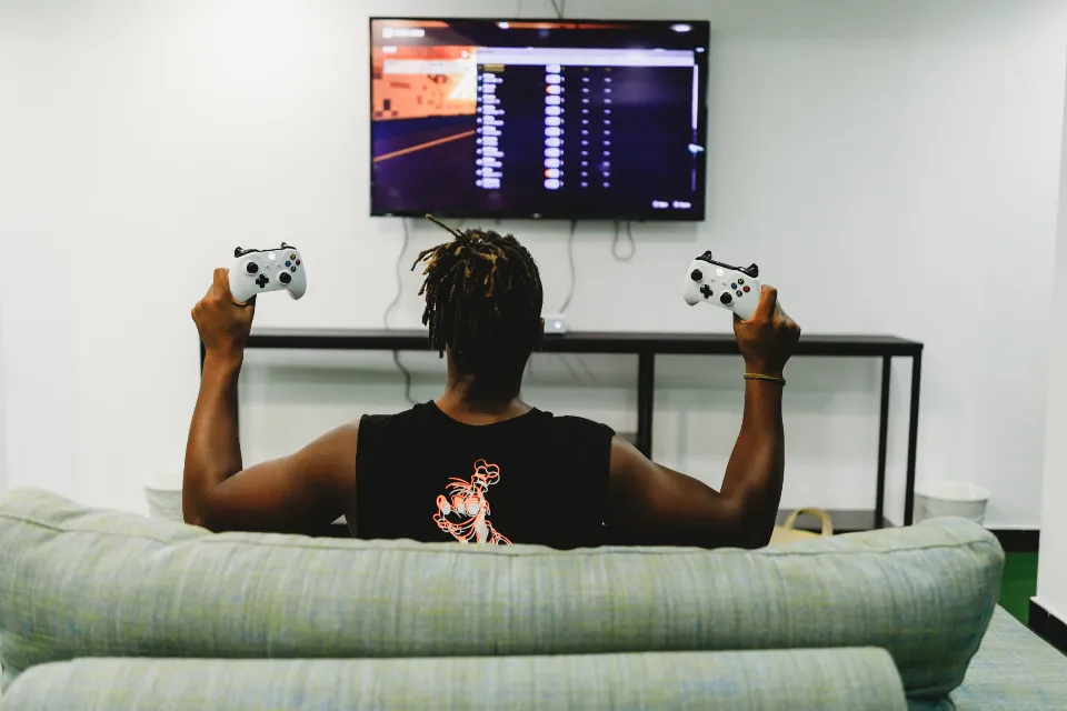Gamer seen from behind holding two controllers in front of a TV