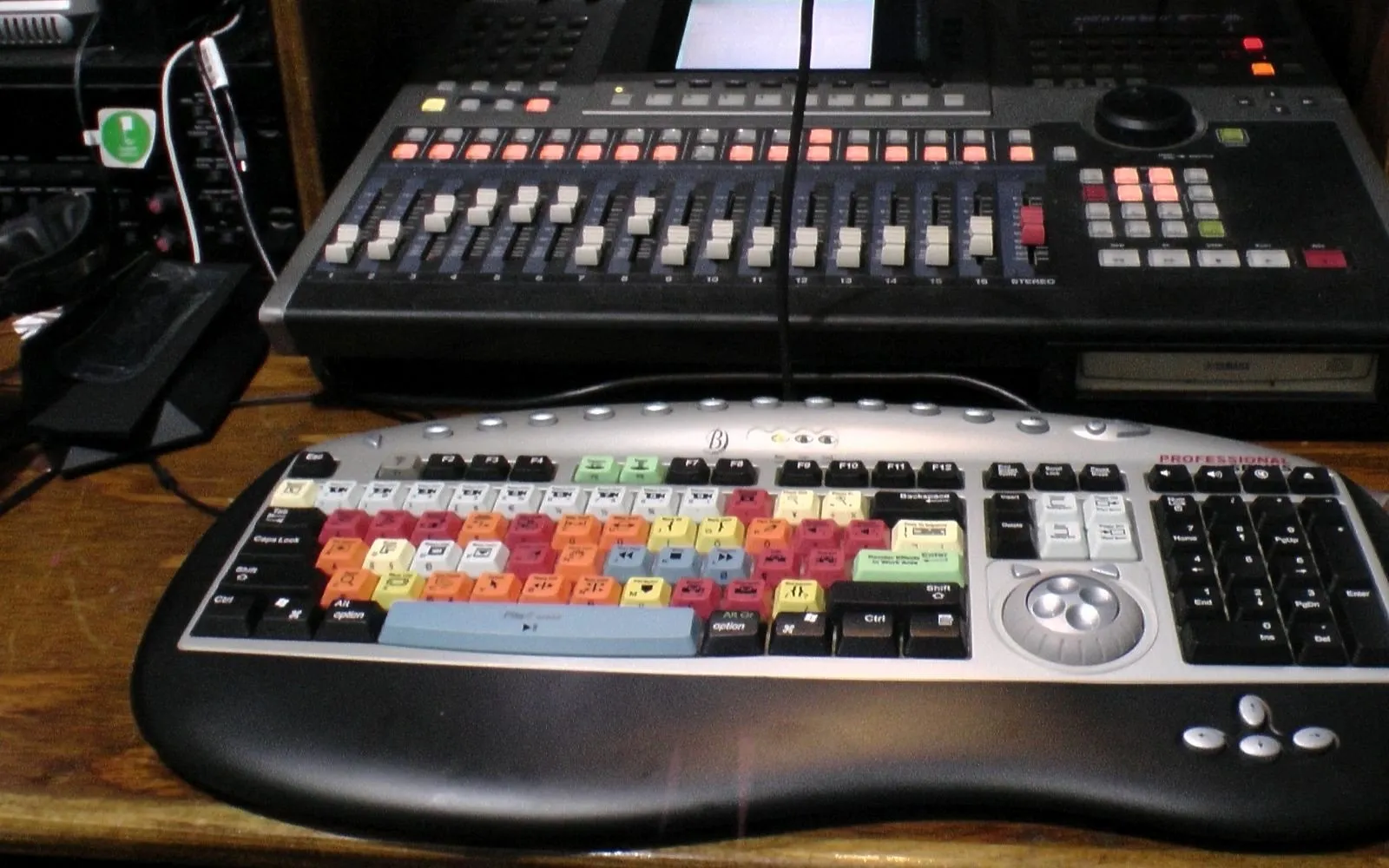 Color-coded video editing keyboard in front of a mixing desk