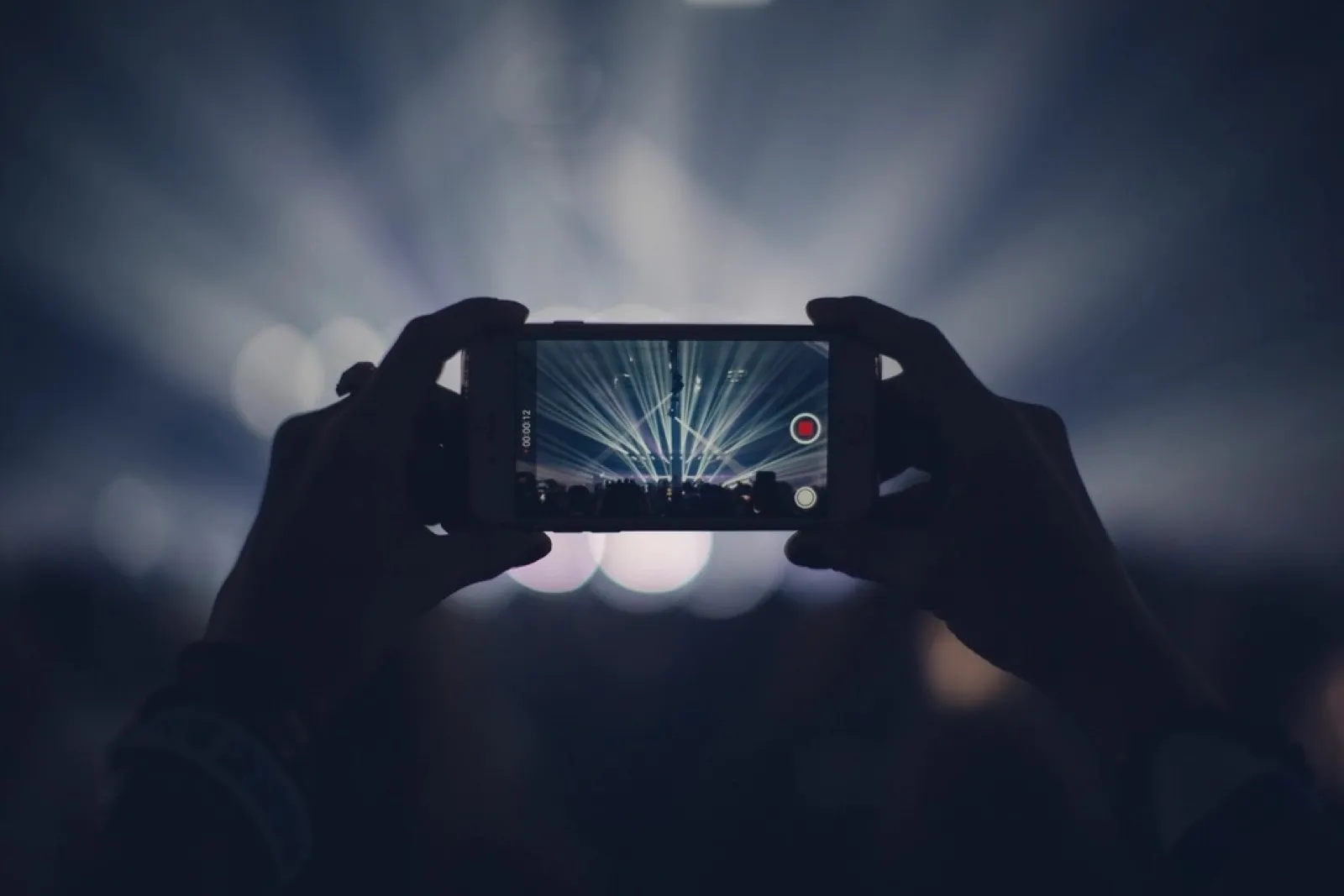 Hands holding a phone, recording video at a concert