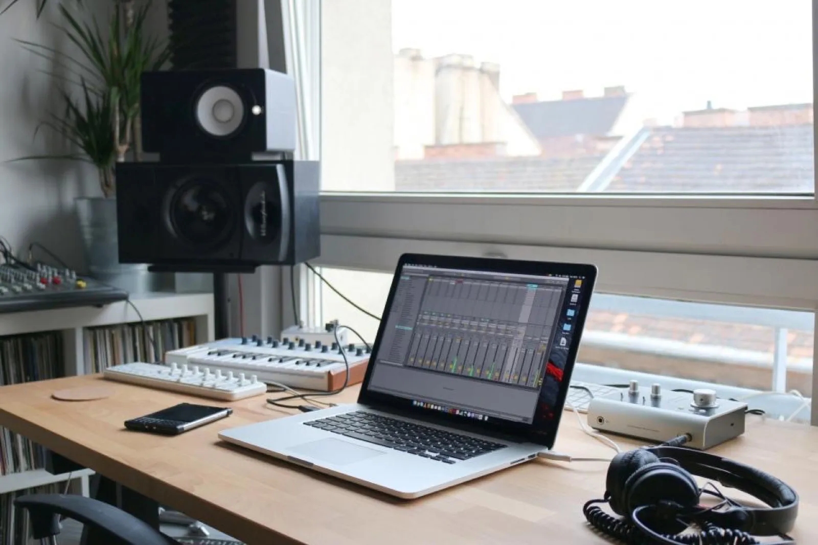 Home studio desk with a laptop showing an editing timeline and headphones